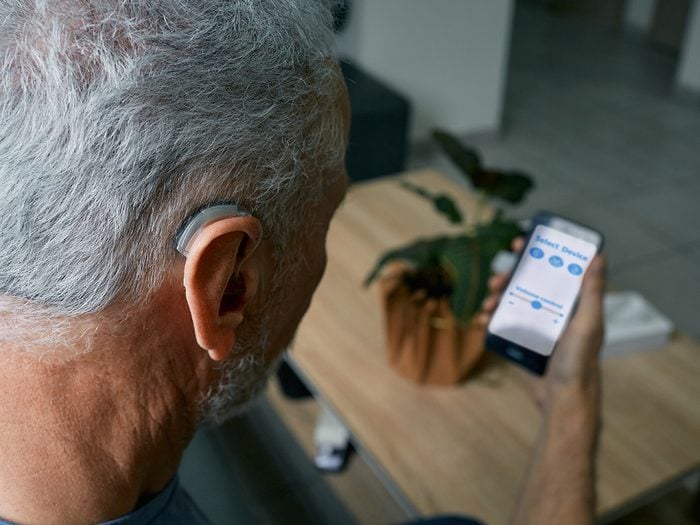 Man controlling hearing aid from phone