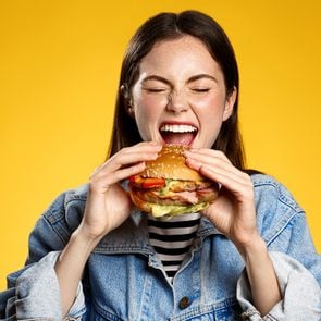 Hamburger Origin - Feature Image (Social) - Woman biting into hamburger