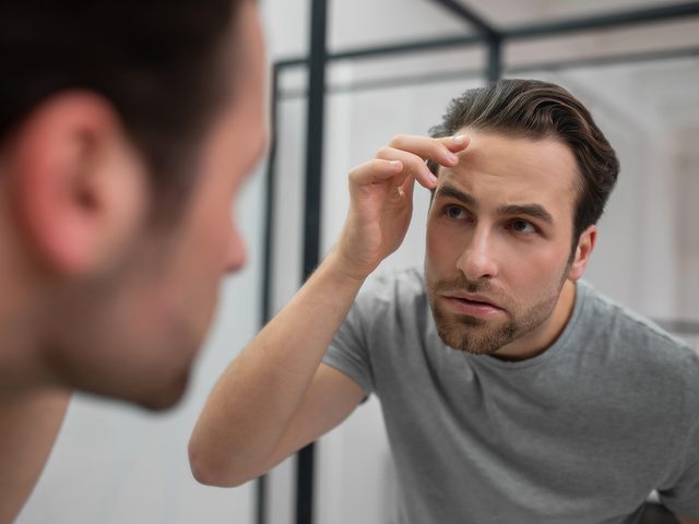 Man Examining Skin in Mirror
