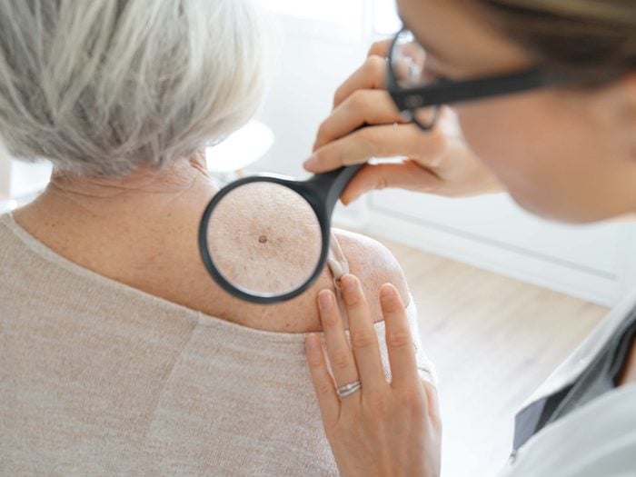 Doctor examining older woman with magnifying glass
