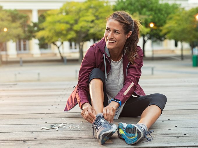 Foot Care - Smiling woman putting on running shoes