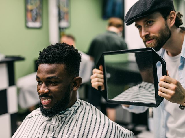 Barber inspects new male client haircut