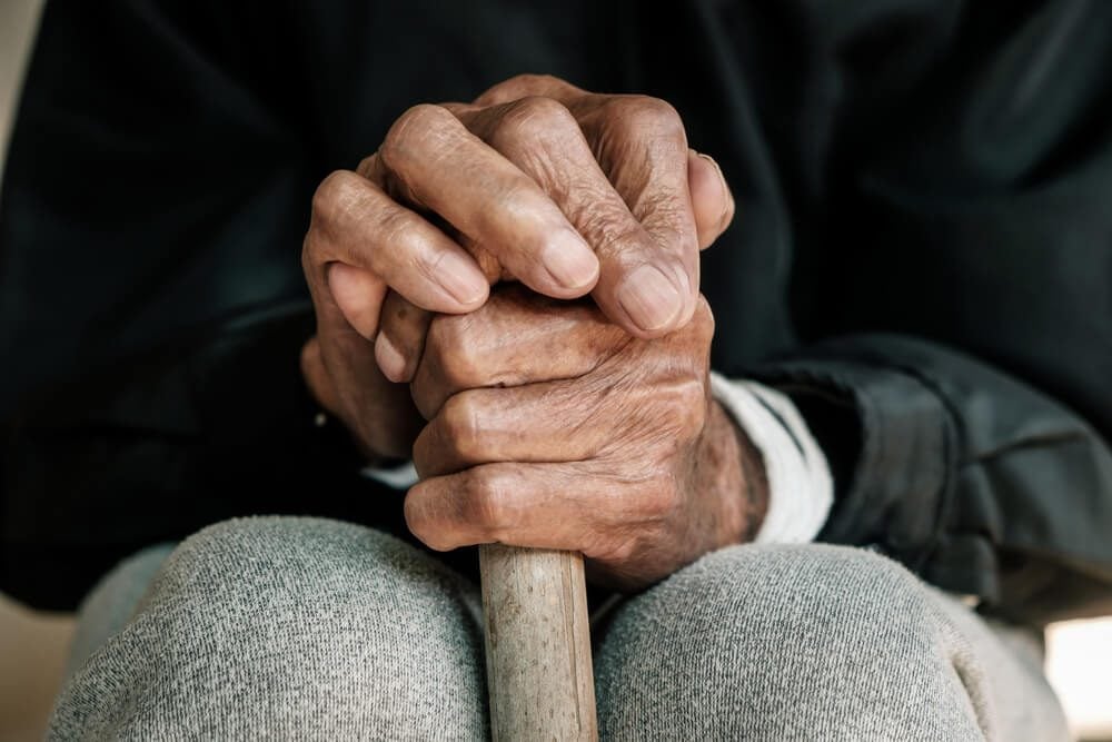 Close-up of elderly hands holding cane