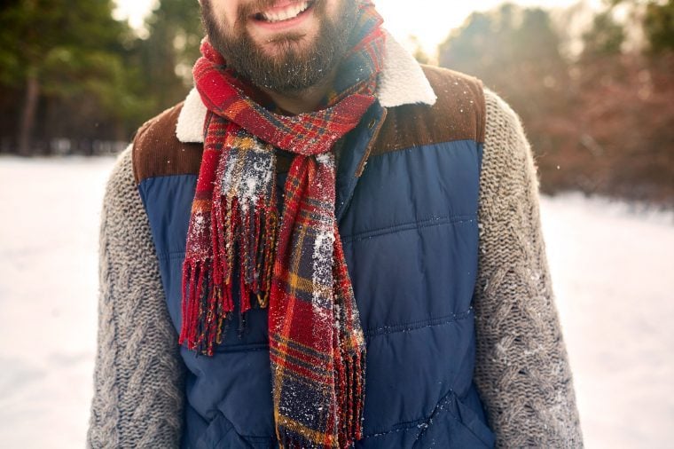 Bearded man in a scarf and winter vest in the snow