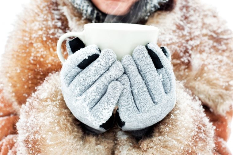 Woman in a fur trimmed collar and gloves holding a mug